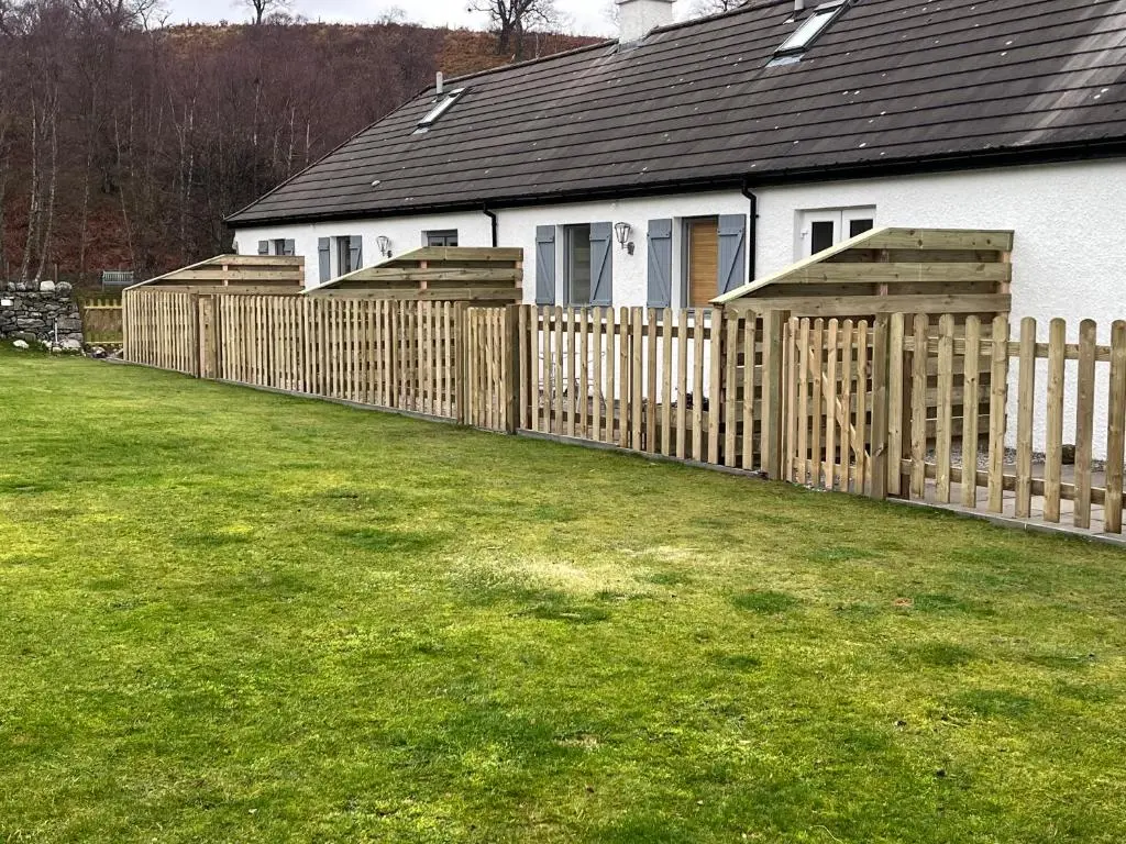 a wooden fence in front of a house at Highland Holiday Cottages in Newtonmore
