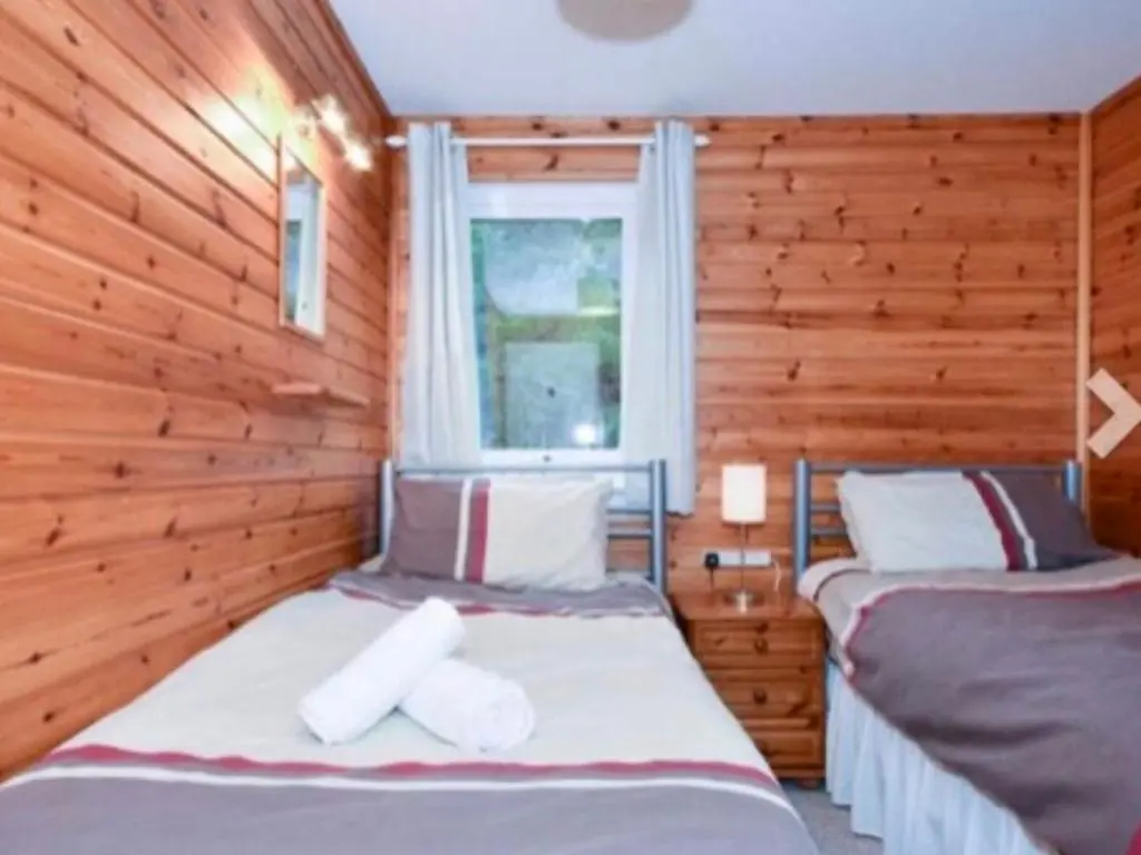 a bedroom with two beds and a window at Ben Rinnes Lodge Glenlivet Highlands in Auchnastank