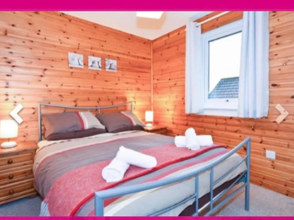 a bedroom with a bed with wooden walls and a window at Ben Rinnes Lodge Glenlivet Highlands in Auchnastank
