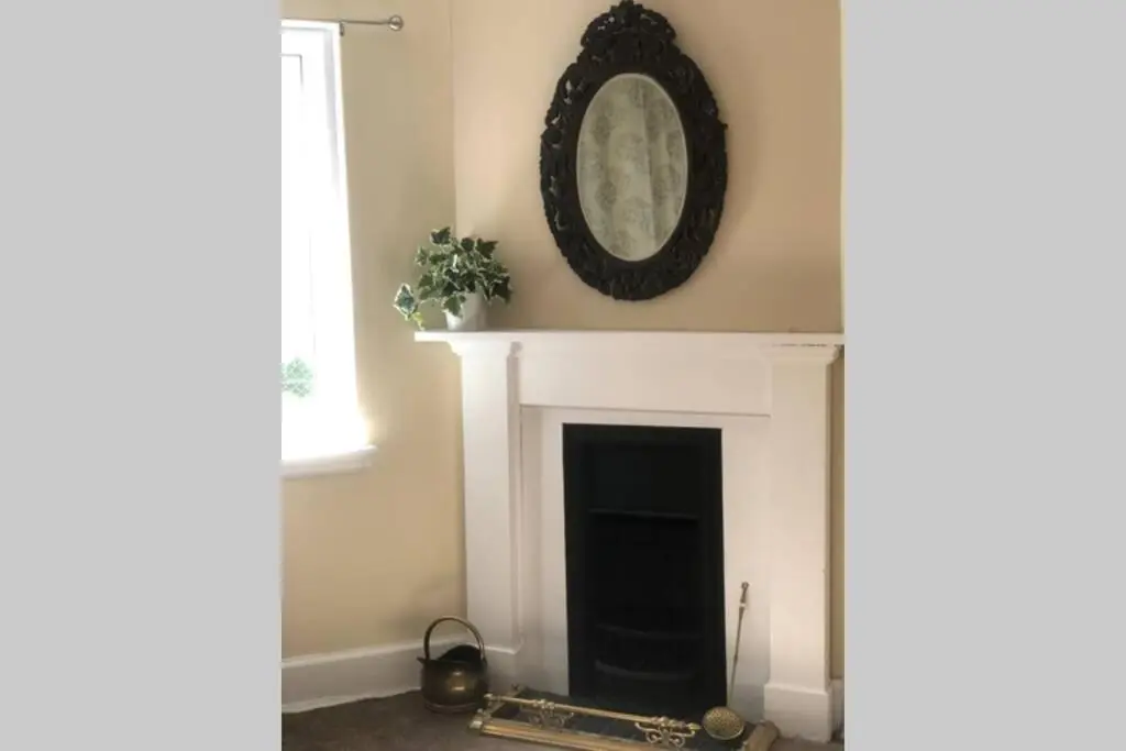 a living room with a fireplace with a clock on the wall at Seacot Cottage in the heart of the Highlands in South Kessock