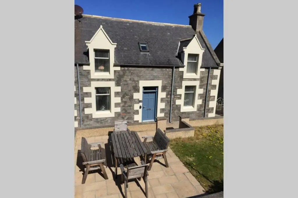 a house with chairs and a table in front of it at Craigewan Cottage Seatown Cullen in Cullen