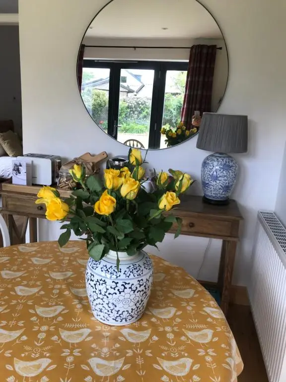 a vase filled with yellow flowers sitting on a table at Garden Retreat - City Central Quiet Garden Apartment with Free Parking in Inverness