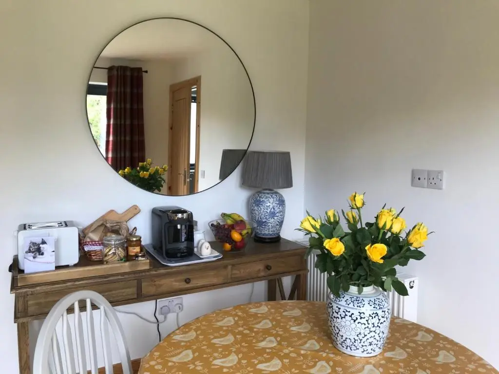 a table with a vase of flowers and a mirror at Garden Retreat - City Central Quiet Garden Apartment with Free Parking in Inverness