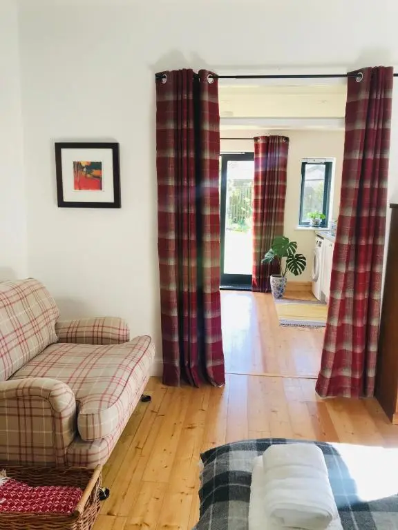 a living room with red curtains and a couch at Garden Retreat - City Central Quiet Garden Apartment with Free Parking in Inverness
