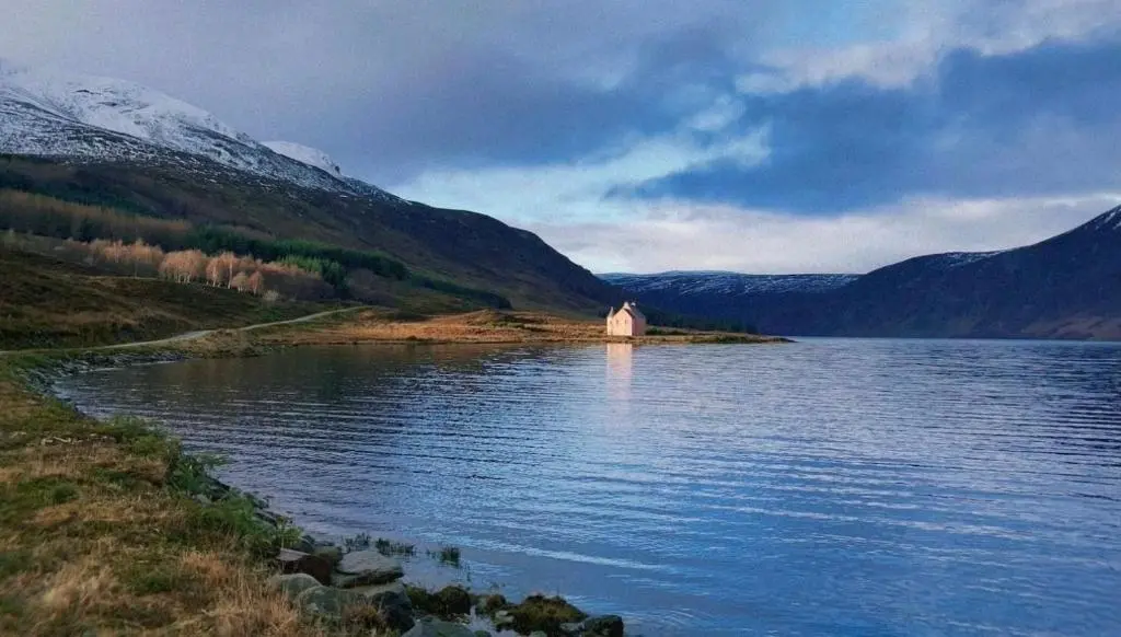 a small building on the shore of a body of water at Garden Retreat - City Central Quiet Garden Apartment with Free Parking in Inverness
