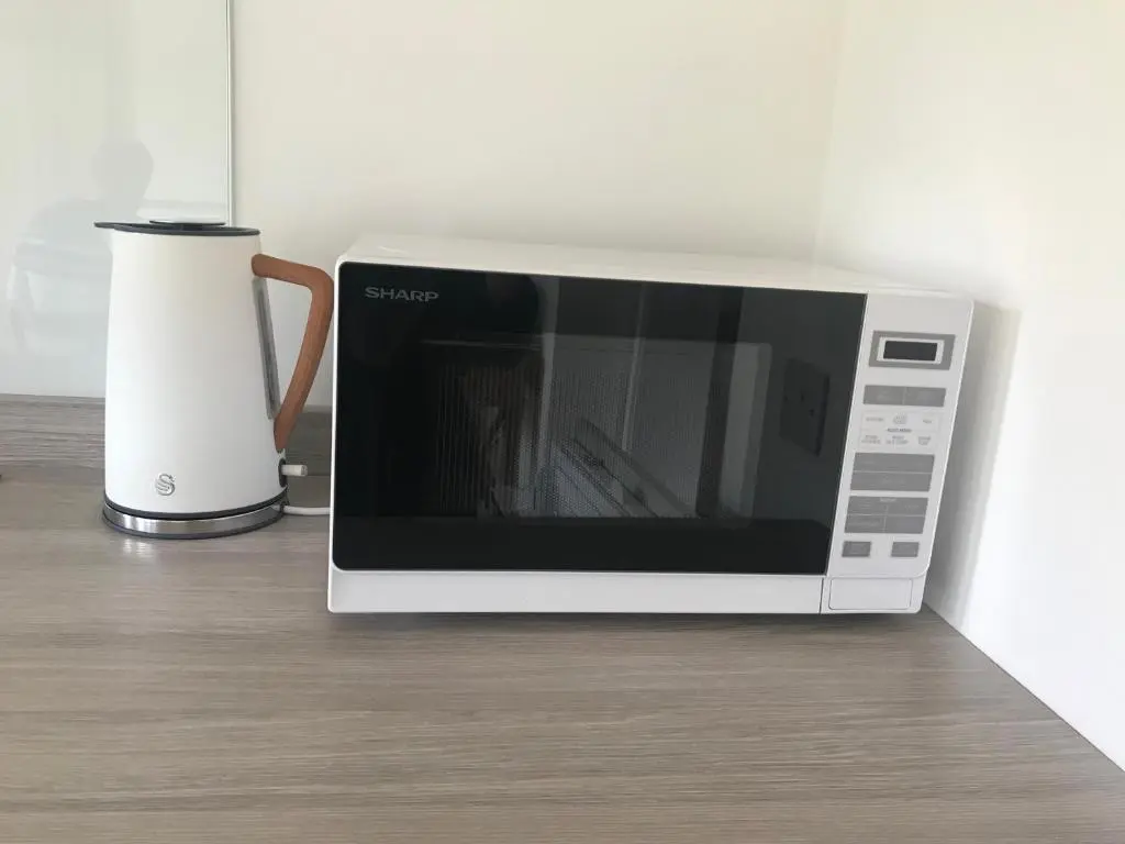 a microwave sitting on a counter next to a vase at Garden Retreat - City Central Quiet Garden Apartment with Free Parking in Inverness