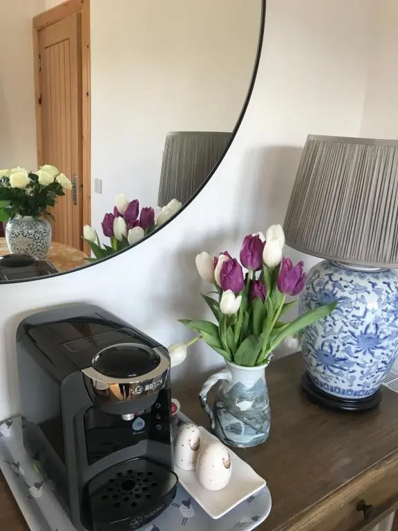 a table with a coffee maker and flowers and a mirror at Garden Retreat - City Central Quiet Garden Apartment with Free Parking in Inverness