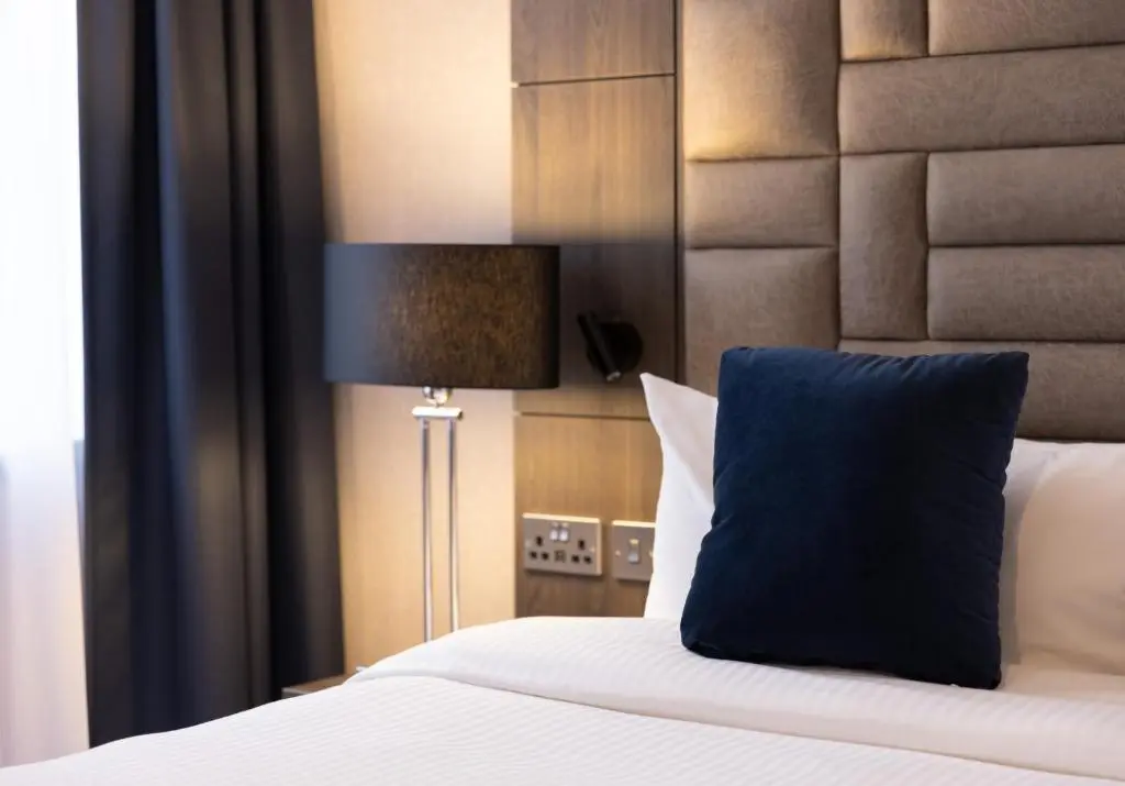 a bedroom with a bed with a blue pillow and a lamp at River Ness Hotel, a member of Radisson Individuals in Inverness