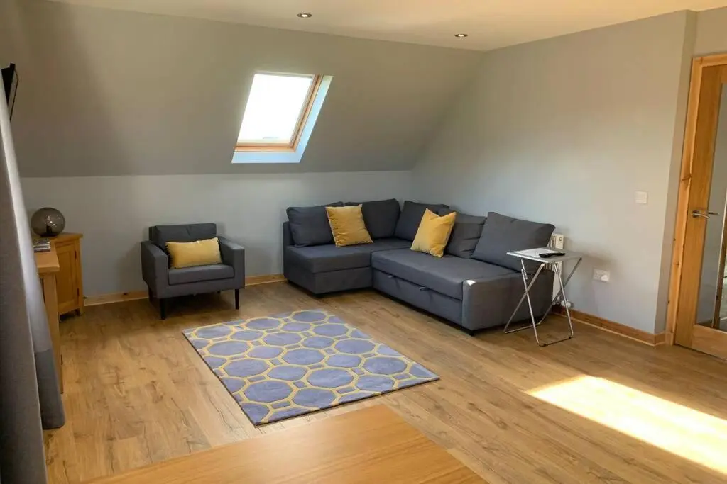 a living room with a blue couch and a chair at The Nest - Near Inverness & Loch Ness in Inverness
