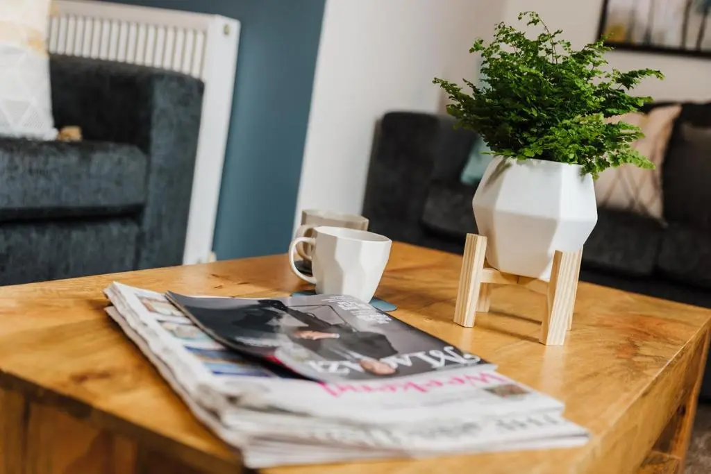 a coffee table with a magazine and a vase on it at Seaforth House Apartment in Elgin