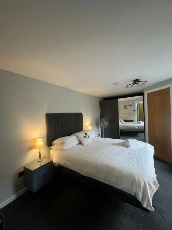 a bedroom with a large white bed with two lamps at Shore Street Apartments in Inverness