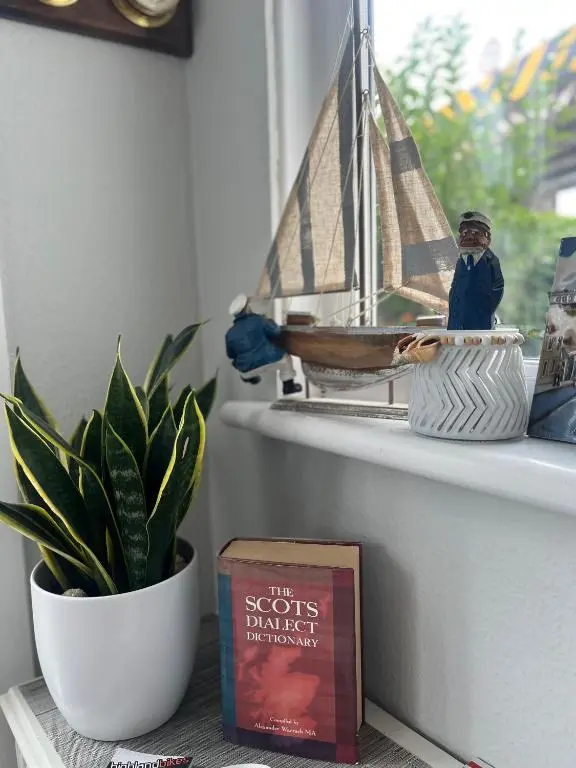 a book and a toy boat on a window sill at Shore Street Apartments in Inverness