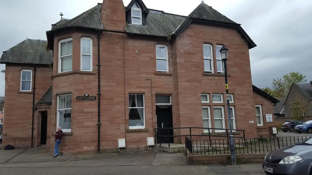 a woman standing in front of a brick building at Flat 1 Castlebank house Flats in Dingwall
