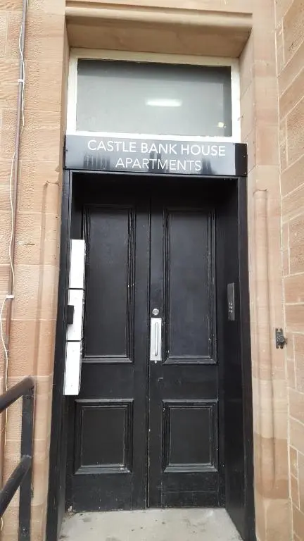 a black door in a building with a sign on it at Flat 1 Castlebank house Flats in Dingwall