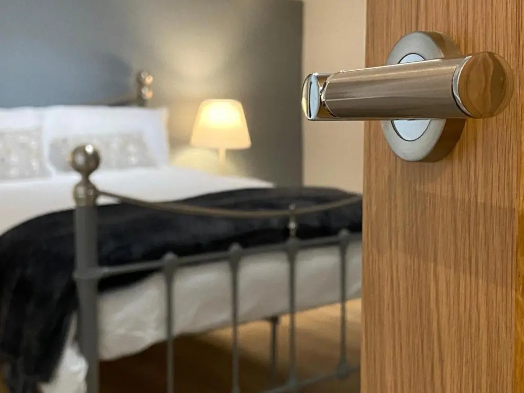a doorhandle to a bedroom with a bed at Islas Cottage, a home in the Heart of Speyside in Dufftown