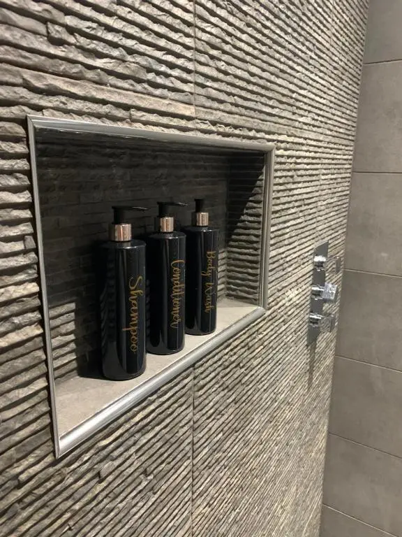 a row of black bottles on a shelf in a brick wall at In the heart of Inverness in Inverness