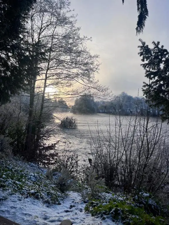 a snow covered field with trees and a body of water at In the heart of Inverness in Inverness