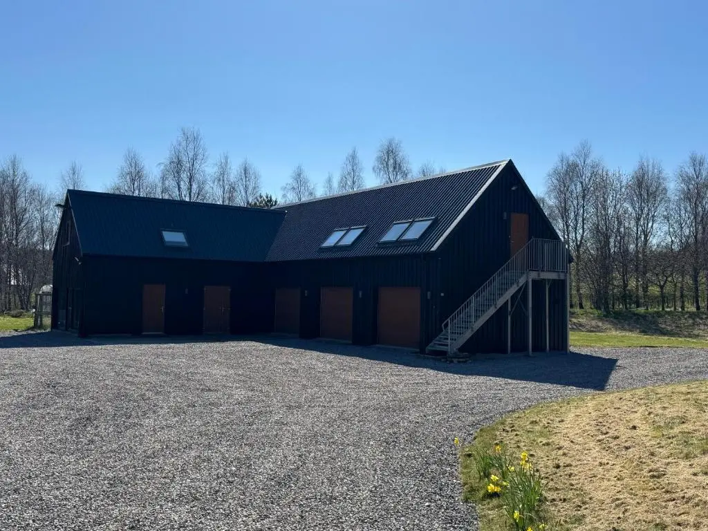 a large black barn with a garage at Willowbarn Rafford Self Catering in Forres