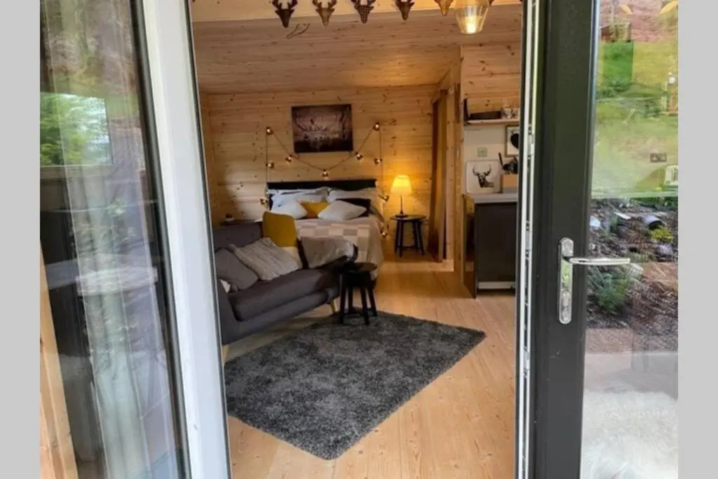 a living room with a couch and a bed at Coorie Doon Cabin! Great Scottish Welcome in Fort Augustus