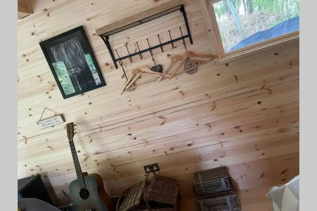 a room with a wooden wall with a guitar at Coorie Doon Cabin! Great Scottish Welcome in Fort Augustus