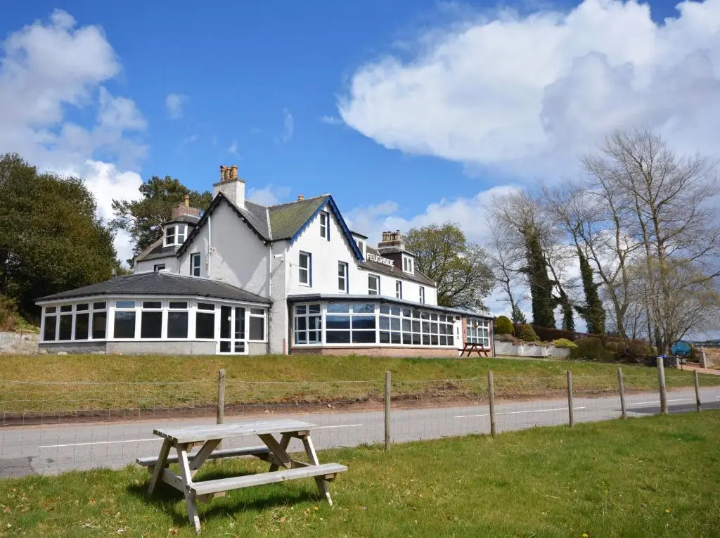 a picnic table in front of a large house at Feughside in Strachan