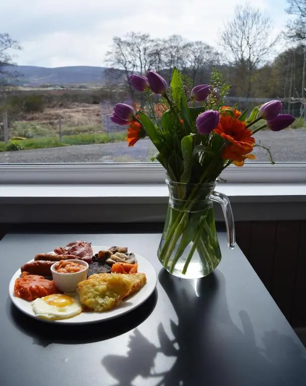 a plate of breakfast food and a vase of flowers at Feughside in Strachan