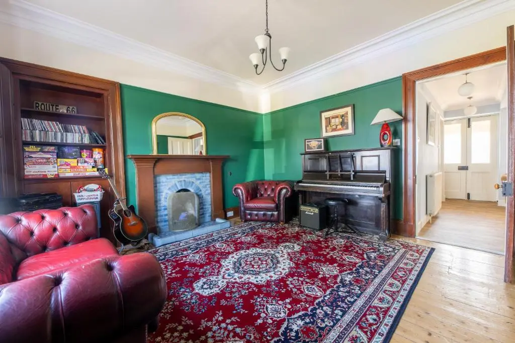 a living room with a red couch and a fireplace at Seaview House - A Traditional Home by the Beach in Nairn