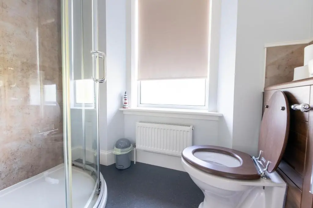 a bathroom with a toilet and a glass shower at Seaview House - A Traditional Home by the Beach in Nairn