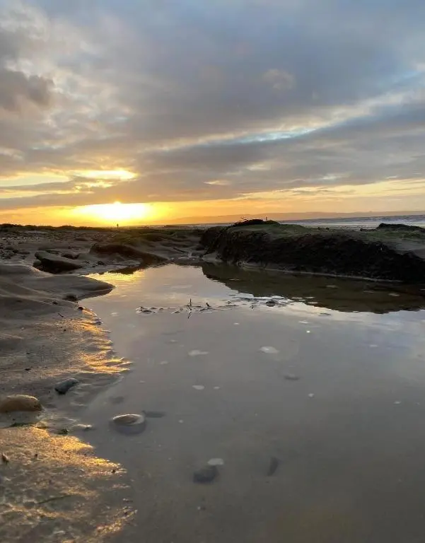 a sunset on a beach with the ocean at Seaview House - A Traditional Home by the Beach in Nairn