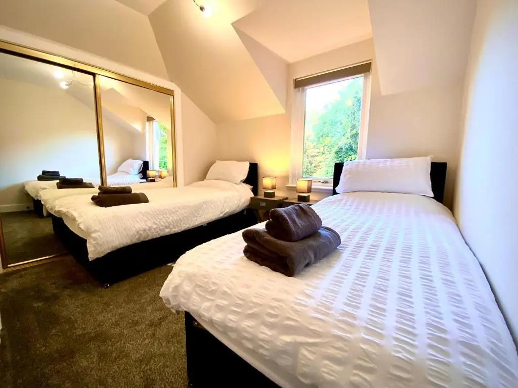 a room with two beds and a mirror at Grampian Serviced Apartments - Treetops Apartments in Elgin