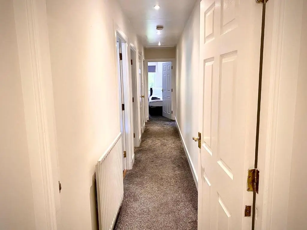 a hallway with white walls and a white door at Grampian Serviced Apartments - Treetops Apartments in Elgin
