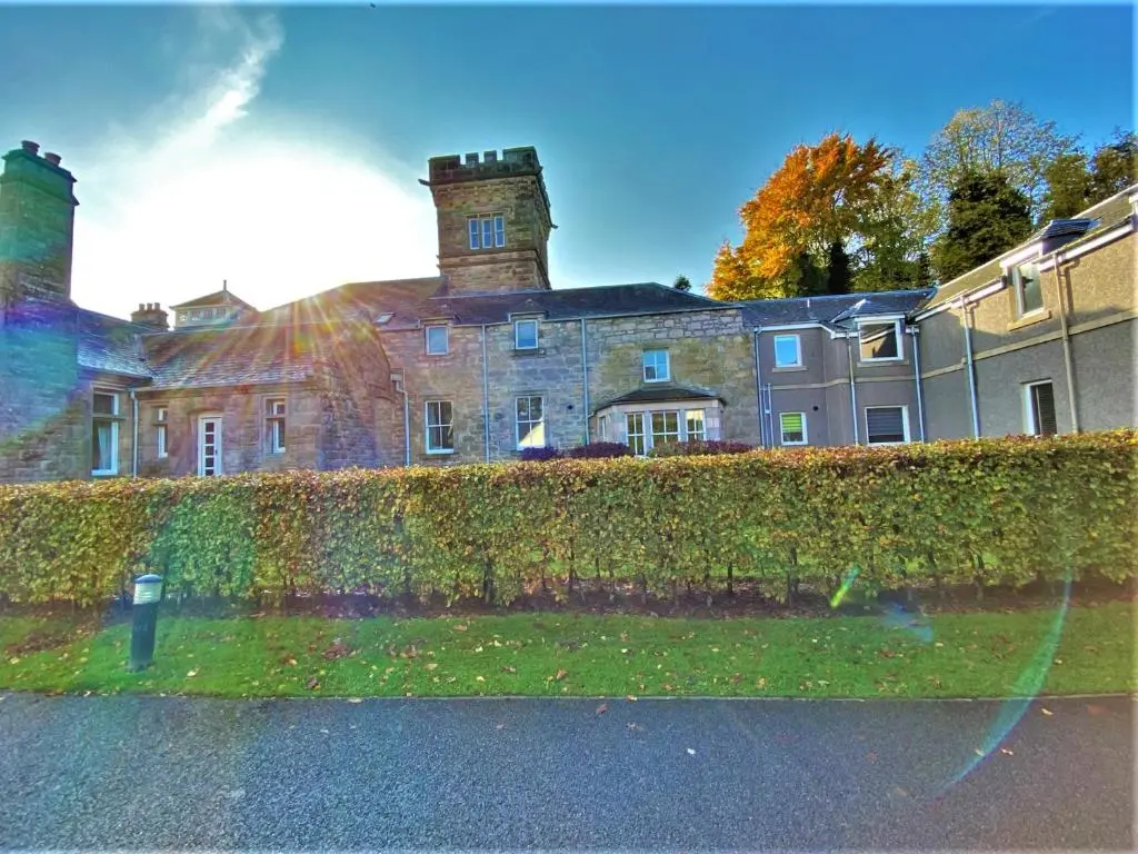 a large brick building behind a hedge in front at Grampian Serviced Apartments - Treetops Apartments in Elgin