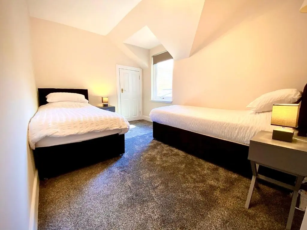 a bedroom with two beds and a window at Grampian Serviced Apartments - Treetops Apartments in Elgin
