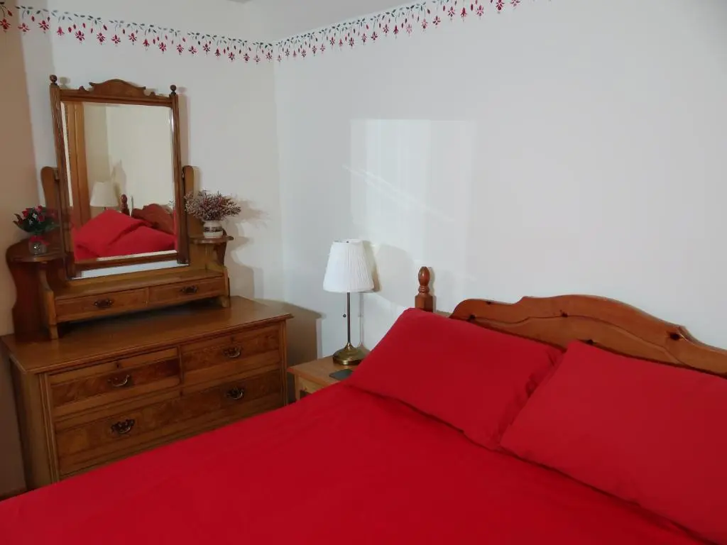 a bedroom with a red bed and a mirror at The Cottage Bogroy in Carrbridge