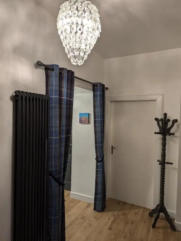 a chandelier and curtains in a room with a door at Shadow's Cottage situated in Fishertown, Nairn. in Nairn