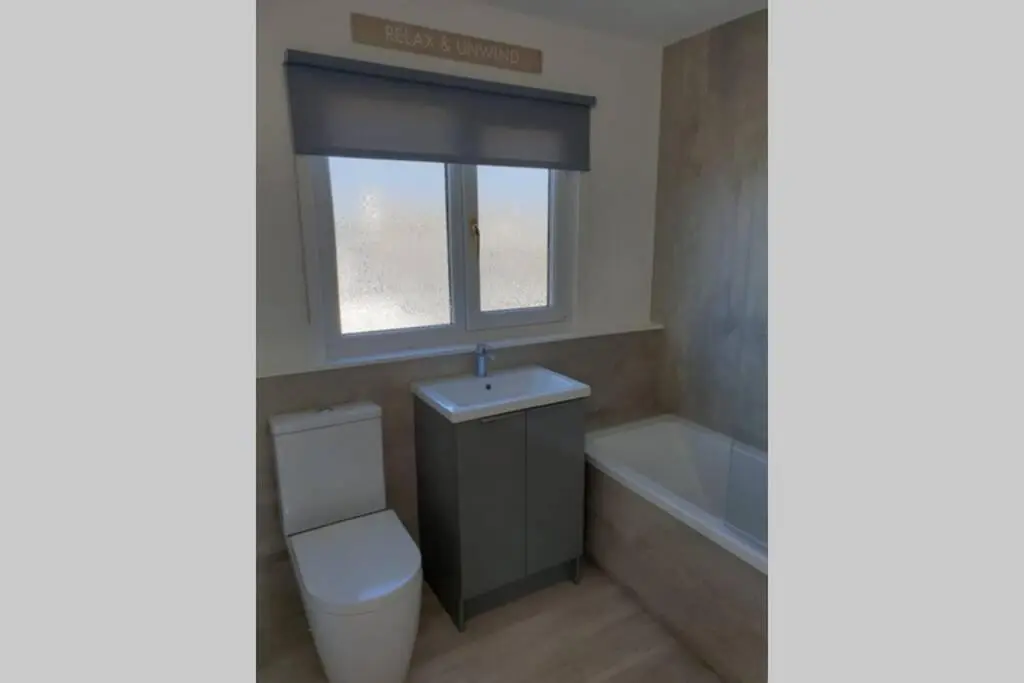 a bathroom with a toilet and a window and a tub at Shadow's Cottage situated in Fishertown, Nairn. in Nairn