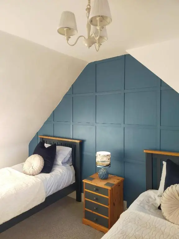 a bedroom with two beds and a blue wall at Shadow's Cottage situated in Fishertown, Nairn. in Nairn