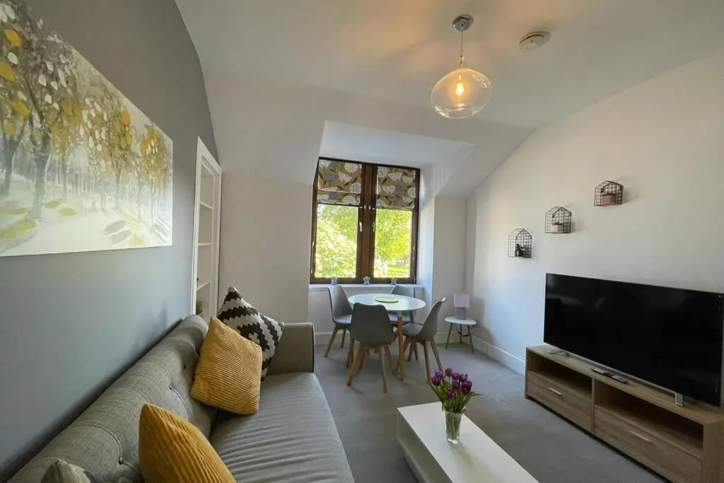 a living room with a couch and a flat screen tv at No 10 Immaculate City Centre, Top Floor 2 Bed Flat with Free Parking in Inverness