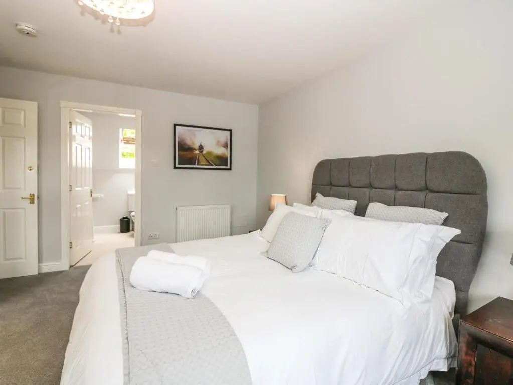 a bedroom with a large white bed with a gray headboard at Tombeck in Tomintoul