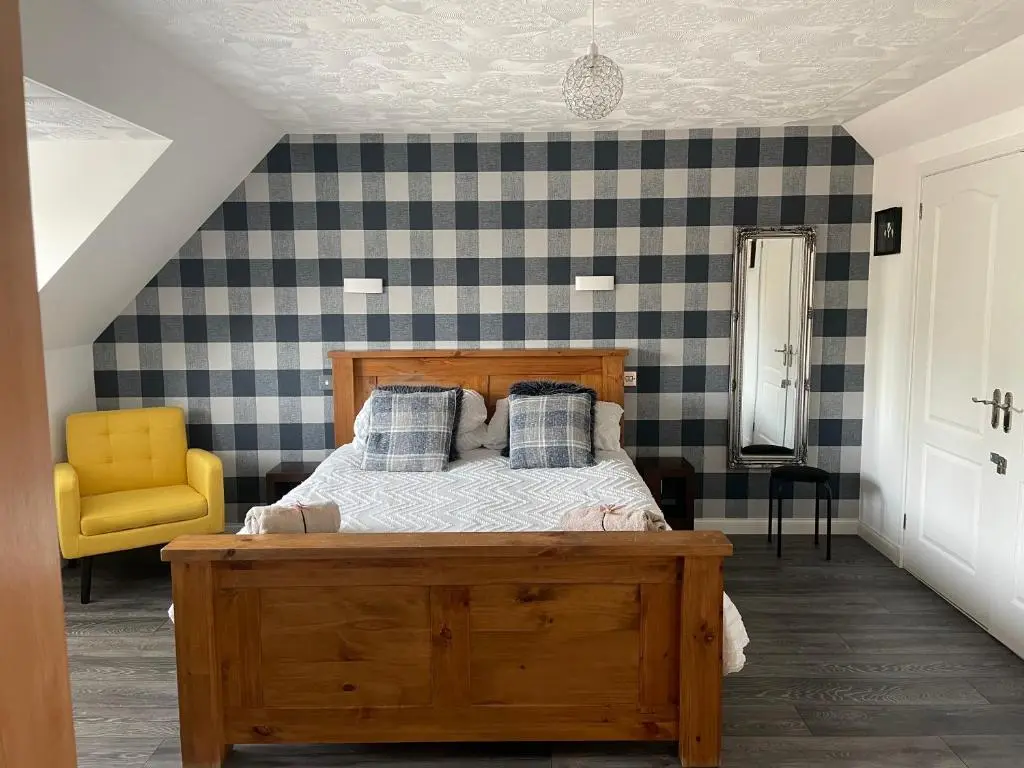 a bedroom with a wooden bed and a yellow chair at Gleneden House in Tore