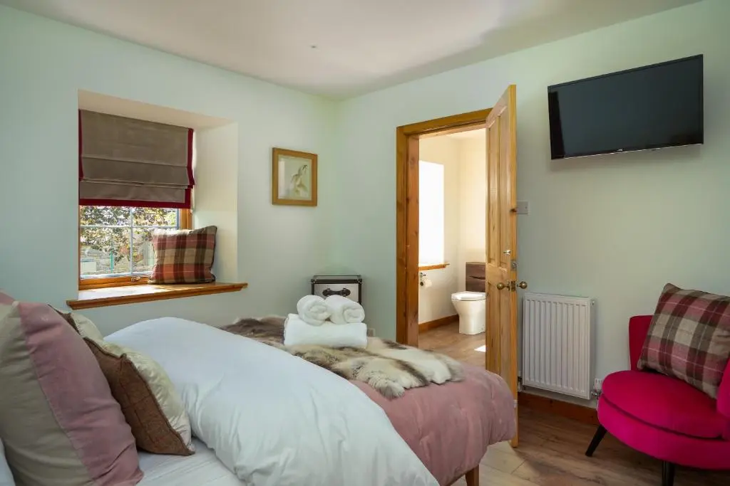 a bedroom with a bed and a tv on the wall at The Eagle's Nest - large house with hot tub and sauna in Boat of Garten