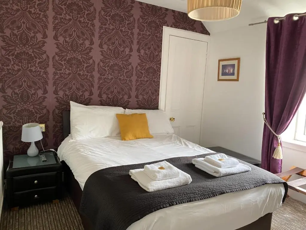 a bedroom with a bed with two towels on it at Richmond House Hotel in Fort Augustus