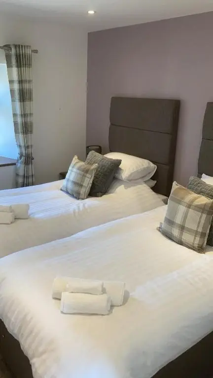 two beds in a room with white sheets and pillows at Meikle Aucheoch Holiday Cottage, plus Hot Tub, Near Maud, in the heart of Aberdeenshire in Peterhead