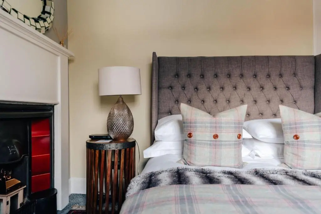 a bedroom with a bed with a headboard and pillows at Luxury Inverness central apartment private parking in Inverness