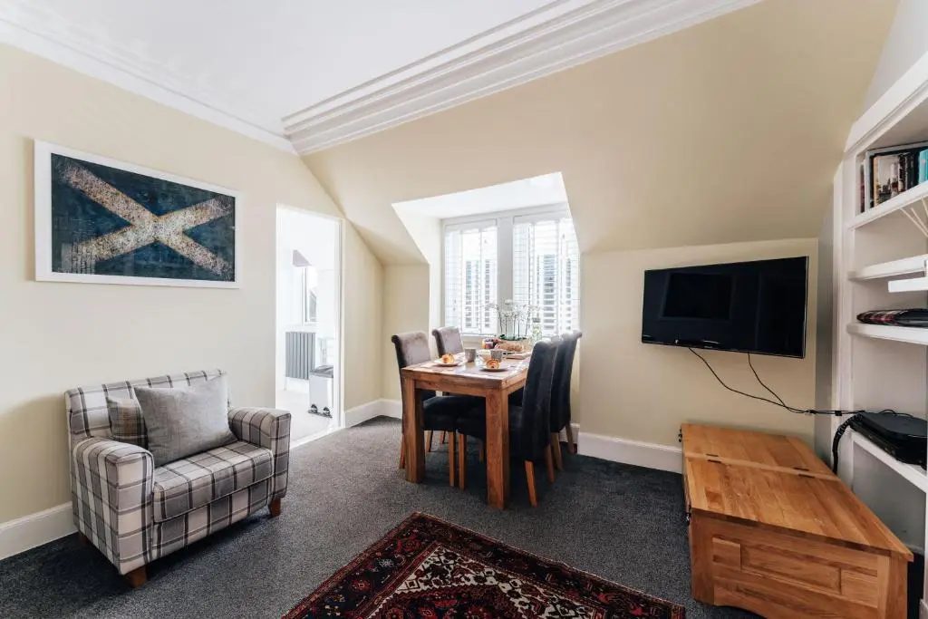 a living room with a table and chairs and a television at Luxury Inverness central apartment private parking in Inverness