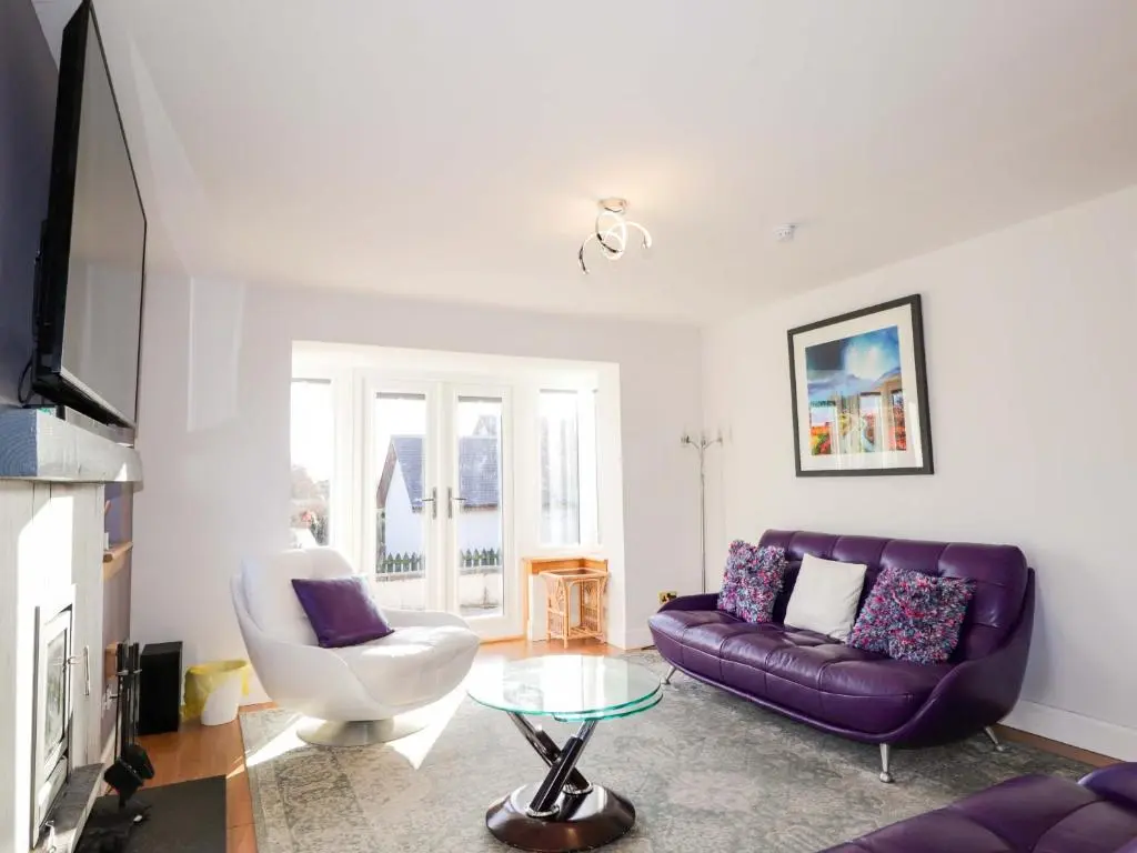 a living room with a purple couch and a table at 3 Croftside in Aviemore