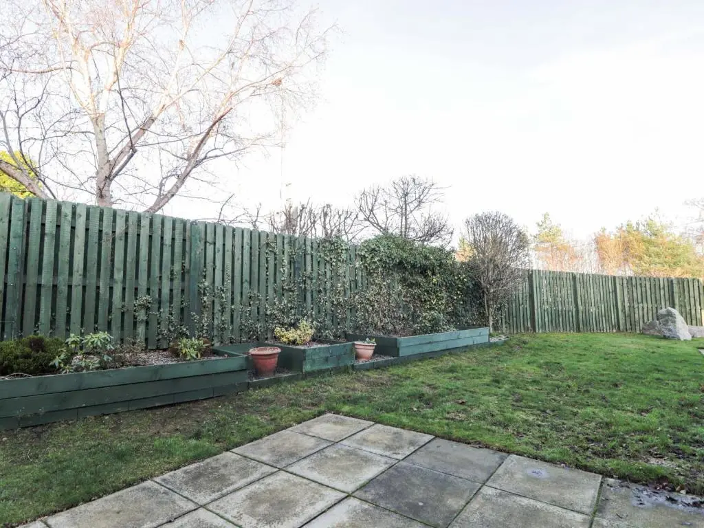 a fence with potted plants in front of a yard at 3 Croftside in Aviemore