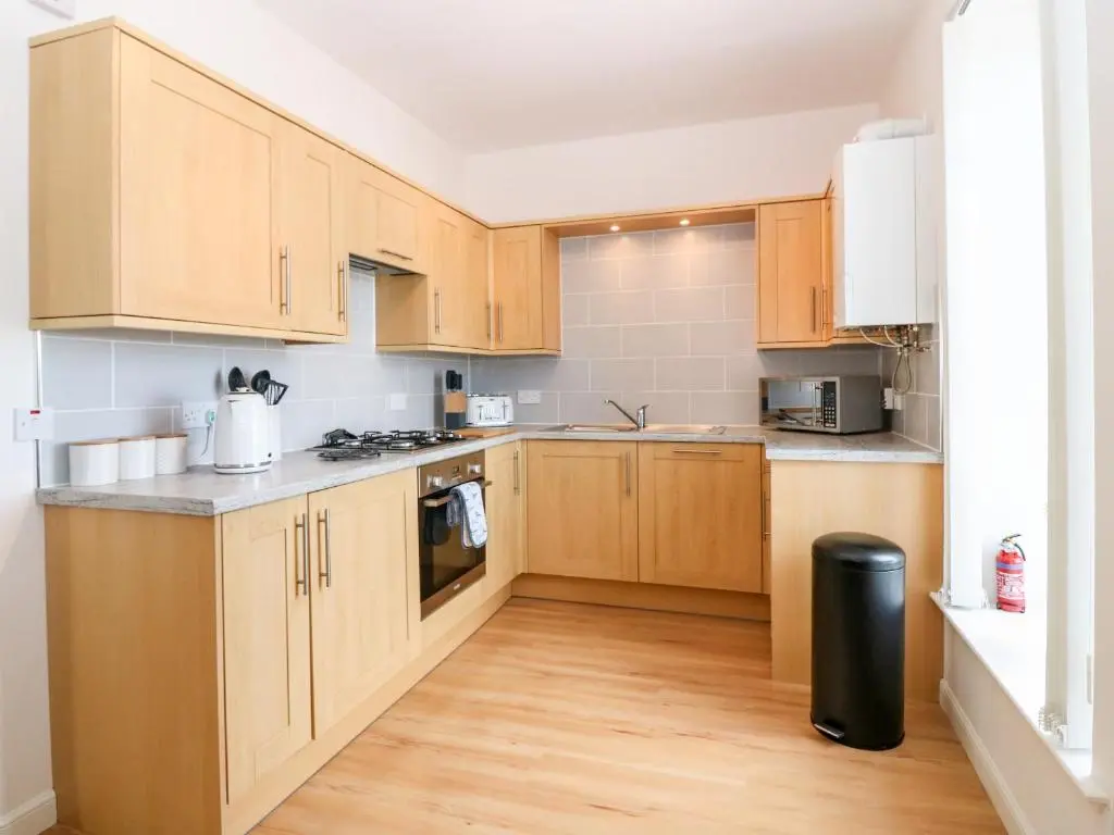 a kitchen with wooden cabinets and a wooden floor at Tammie Norrie Cottage in Banff