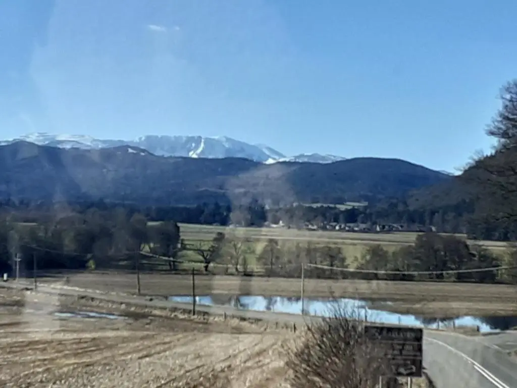 a field with a road and mountains in the background at Just off the Square... Ballater in Ballater