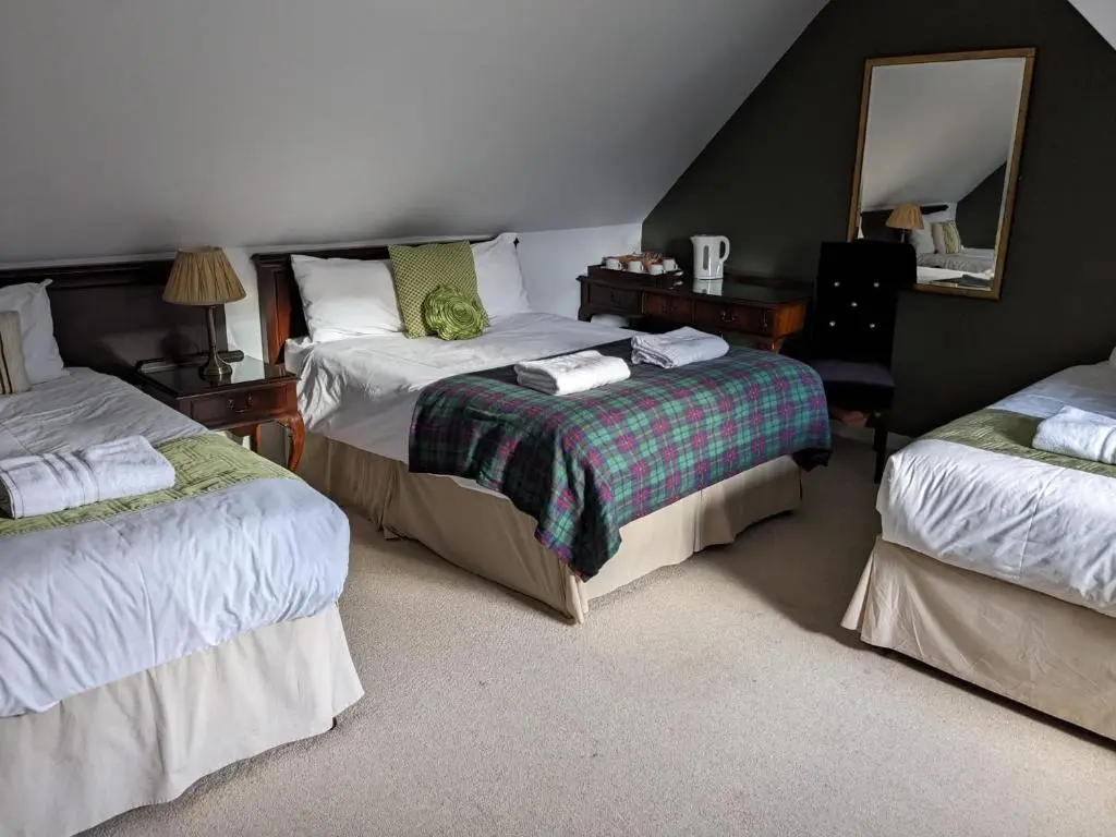 a bedroom with two beds and a mirror at Bennachie Lodge Hotel in Kemnay in Inverurie